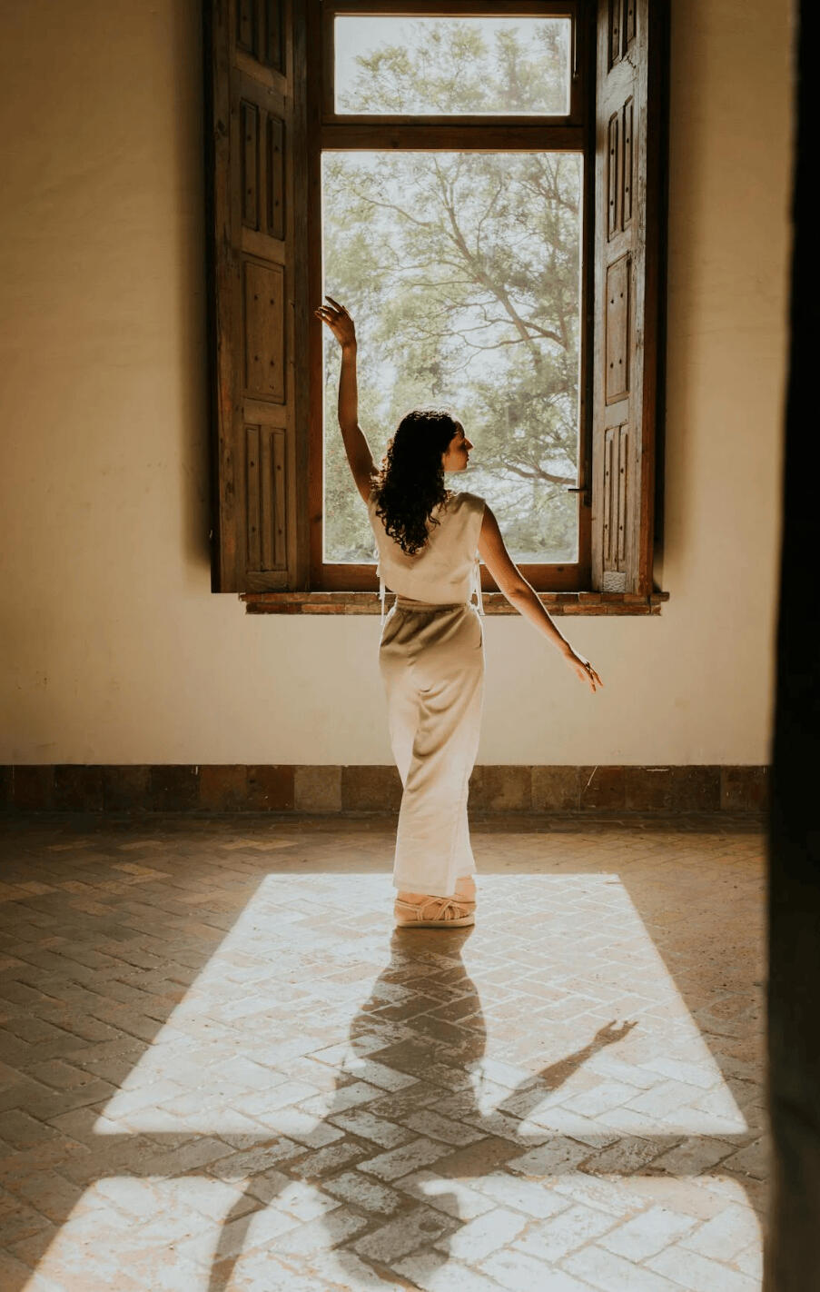 Live 1:1 Psychic Reading Psychic Bii Biis Botanica A woman free and happy in front of a window after receiving a live psychic reading and consultation
